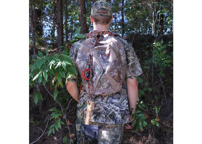Person in full camouflage gear with a bow and arrow, standing in a forest setting.