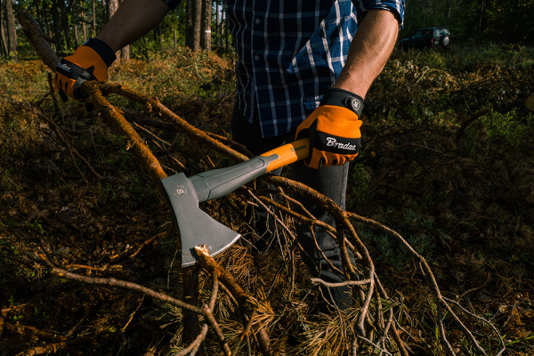 Person using a Brander axe to cut through wood in a forest setting