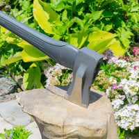 Garden tool on a rock with greenery and flowers in the background