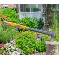 Garden axe with an orange handle and gray head on a garden background