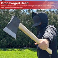 Person holding an axe with a drop forged head in a grassy area