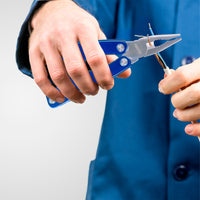 Person using blue pliers to cut a wire against a white background