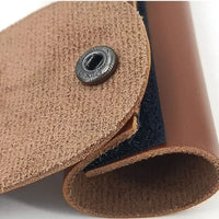 Close-up of a brown leather product with a button on a white background